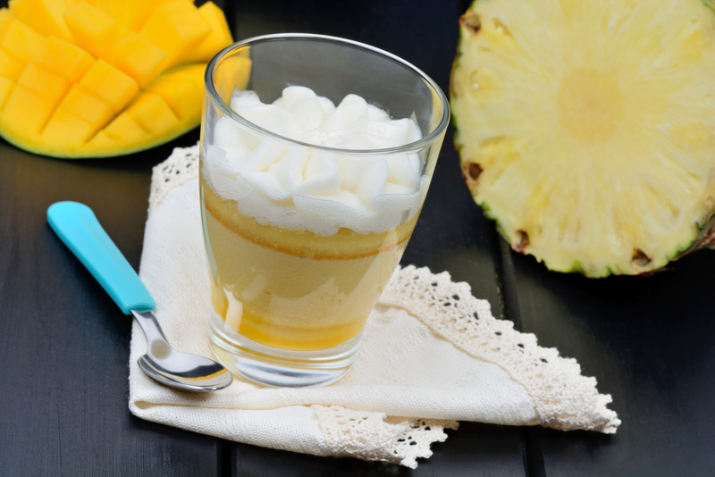 Mousse of mango fruit and pineapple in a glass jar on black table